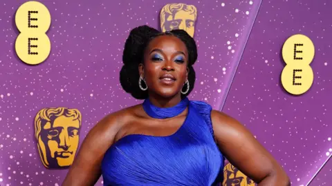 Getty Images Wunmi Mosaku in a blue off the shoulder dress on the red carpet