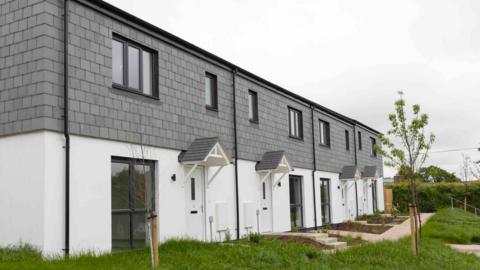 A terrace of four new two-storey homes in Callington, with white-walled ground floors and a slate-fronted first floor