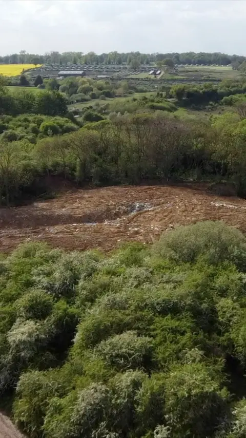 A drone image showing a large waste dump. It is surrounded by woodland.