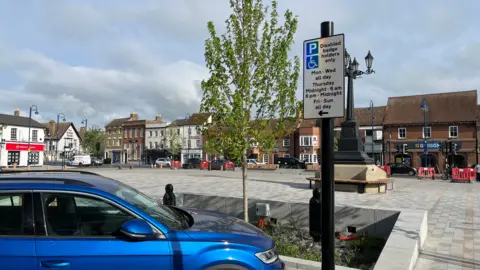 Tom Jackson/BBC View of a blue car parked at the side of the market square. In front of it on a black pole is a sign stating "Disabled badge holders only".