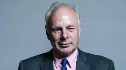 UK Parliament A man with white hair and a pink shirt