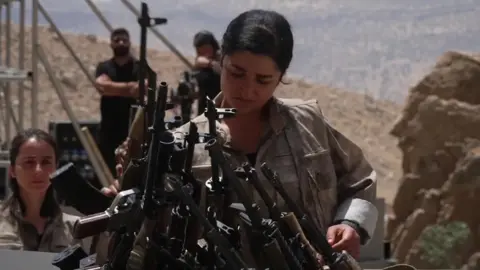 A woman places a gun in a cauldron