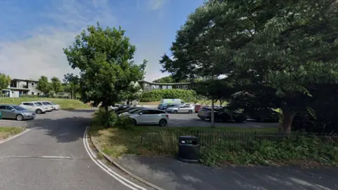 The car park of a GP surgery surrounded by trees. 