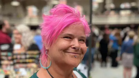 A photograph of a woman with pink hair at the opening of the market