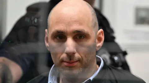 A man behind a glass screen