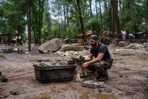 Man sifts through muddied objects