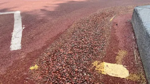 A red road where double yellow lines have stones over them.