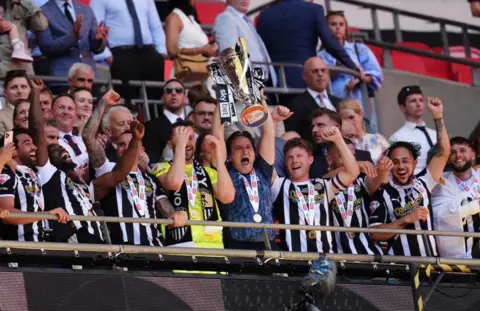 PA Media Notts County celebrate with the trophy aloft on the Wembley balcony