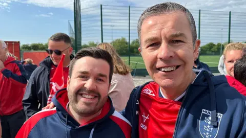 Matt Dean/BBC Steve and Scott Marshall. Son Scott has short dark hair and beard and is wearing a red and blue jacket. Steve has short dark hair and is wearing a red Hull KR shirt and blue and red tracksuit top.