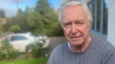 Photograph of Mike Cummings from Cheshire. He is pictured outside his home in Adlington