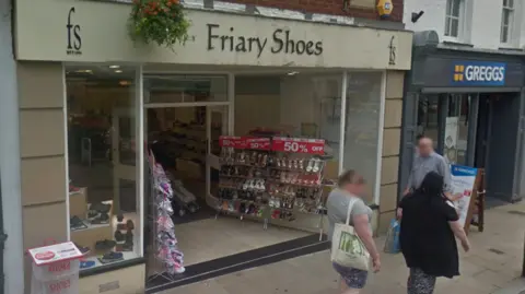 Google The shop has a beige sign and a light brown finish externally and shoe racks outside its entrance.