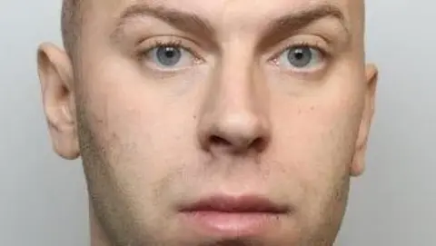 Police mugshot of Cameron Evans, who has blue eyes and shaved brown hair.