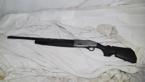 Bedfordshire Police A shotgun lying on untidy bed covers.