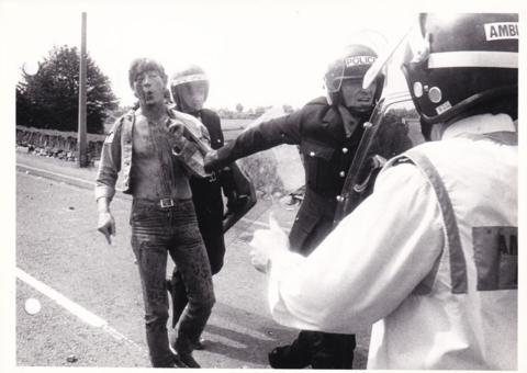 A bloodied miner is arrested by police