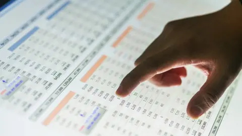 Getty Images A hand pointing to a data list on a computer screen