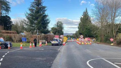 Lots of road signs and cones close the road through the village. 