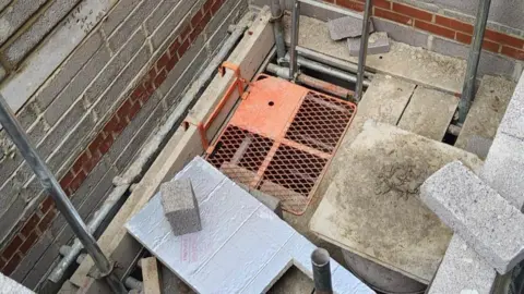 Trowbridge Town Hall Trust Looking down into bricks and scaffolding in a rectangle shape as the start of building a lift shaft