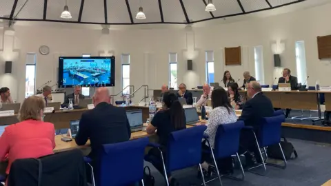Shot of the cabinet members dicussing plans around a 'u' shaped table 