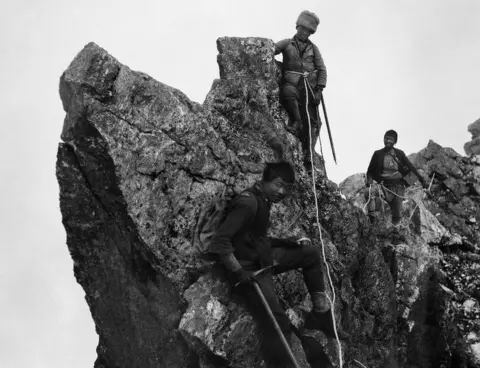 RGS-IBG/Salto-Ulbeek Three porters climbing along a ridge