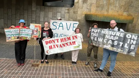 Five wildlife protesters hold up banners opposing the scheme. One reads: "Hands off Havannah" while another says: "Put nature on the map in Newcastle".