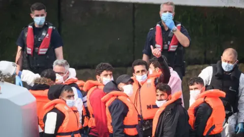 Getty Images Migrants with border force officials on boat