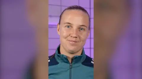 Beth Mead smiling to camera, with hair scraped back against a purple background.