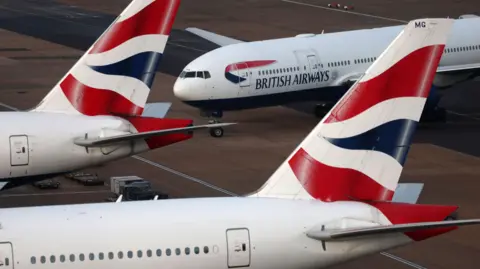 Three red, white and blue British Airways planes at a airport.