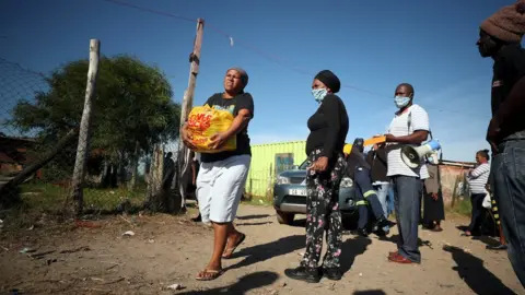 Reuters A township resident carries a food package handed out by a non governmental organisation during a 21-day nationwide lockdown aimed at limiting the spread of the coronavirus disease