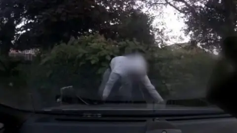 Person with blurred face in front of car
