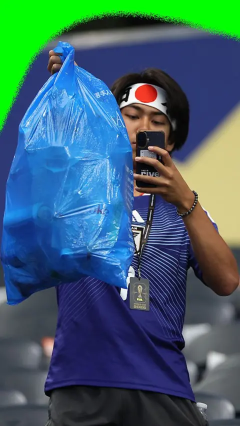 Japan fan takes photo of bin bag after tidying up after their World Cup match against Netherlands
