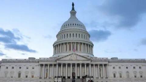 A front view of the US Capitol, with a large white dome