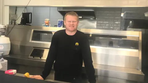 NFFF President of the National Federation of Fish Friers, behind the counter of a fish and chip shop