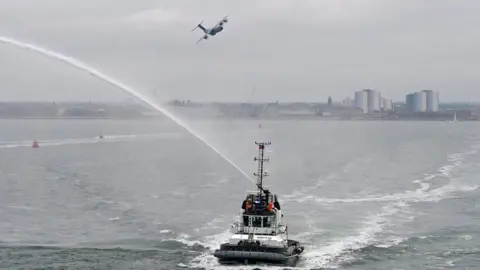 PA Media Flypast by RAF A400s and tugboats spray the water as a ferry with veterans leaves Portsmouth