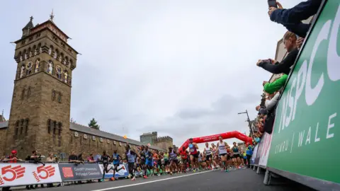 Run 4 Wales Runners in the marathon in the distance while running in front of Cardiff Castle