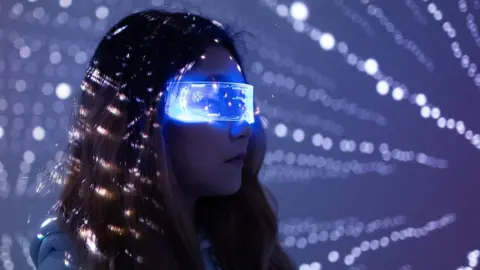 Getty Images A woman wears augmented reality glasses in a dark room with white dotted lights in the background