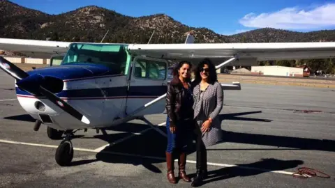 Supplied Two women smiling in front of a light aircraft on a runway, with Californian-looking landscape behind them