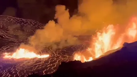 Lava erupts from a volcano seen from above at night