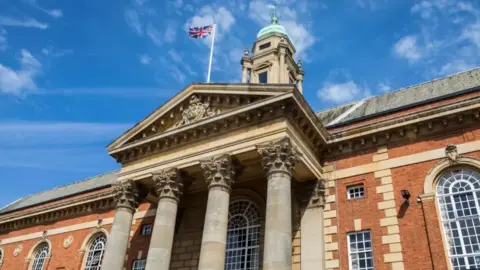 Front of Peterborough town hall, a red-brick building with four columns by the entrance.