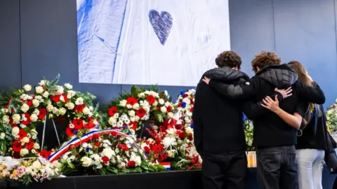 EPA/Shutterstock Victims' relatives observe a moment of silence at a commemorative ceremony and the national day of mourning in Martigny, Switzerland. Photo: 9 January 2026