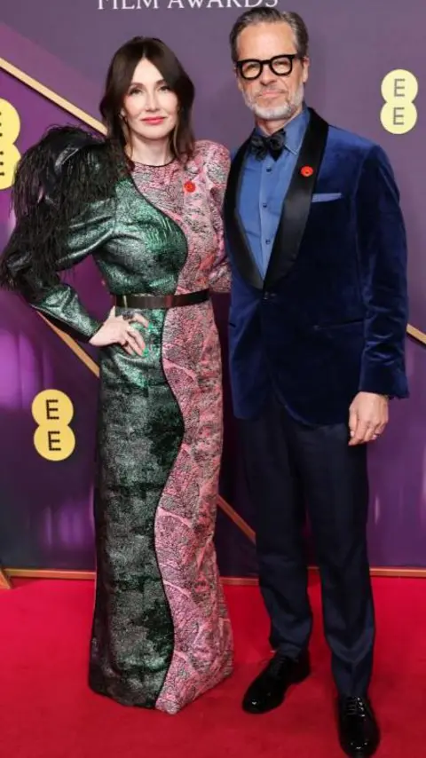 Getty Images Carice van Houten and Guy Pearce; she is in a green and pink dress and he is in a blue, velvet suit