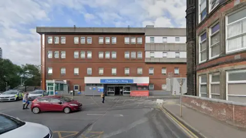 The A&E department at St James's Hospital in Leeds, a red brick four-storey building with a car park in front