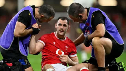 Tomos Williams is treated by team medics while he sits on the field during Wales' game against Fiji