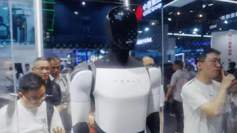 Visitors look at Tesla humanoid robot on display at an AI conference in China.