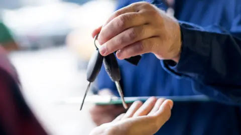Getty Images Many hands over car keys to somebody else