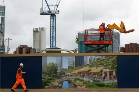 Getty Images A construction worker passes a hoarding surrounding the One Thames City development in London