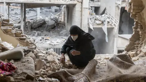 A woman sifts through the rubble in her house in the Beryanak District after it was damaged by missile attacks two days before, on March 15, 2026 in Tehran, Iran.