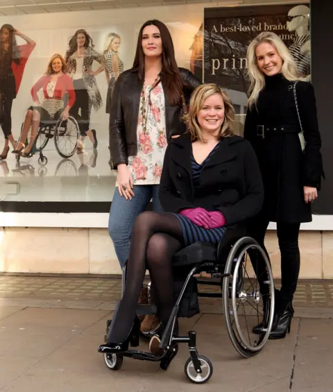 Getty Images Three models stand in front of a window display