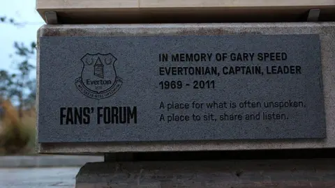 Getty Images View of plaque on the side of the bench. It says "In memory of Gary Speed - Evertonian, captain, leader - 1969-2011. A place for what is often unspoken. A place to sit, share and listen". 