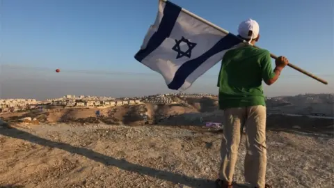 AFP Jewish youth holds Israeli flag near Jewish settlement of Maale Adumim (file photo)