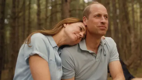 Will Warr/Kensington Palace Catherine and William gaze into the distance while holding one another in a forest clearing Norfolk in the film which is filtered to appear sepia in tone.